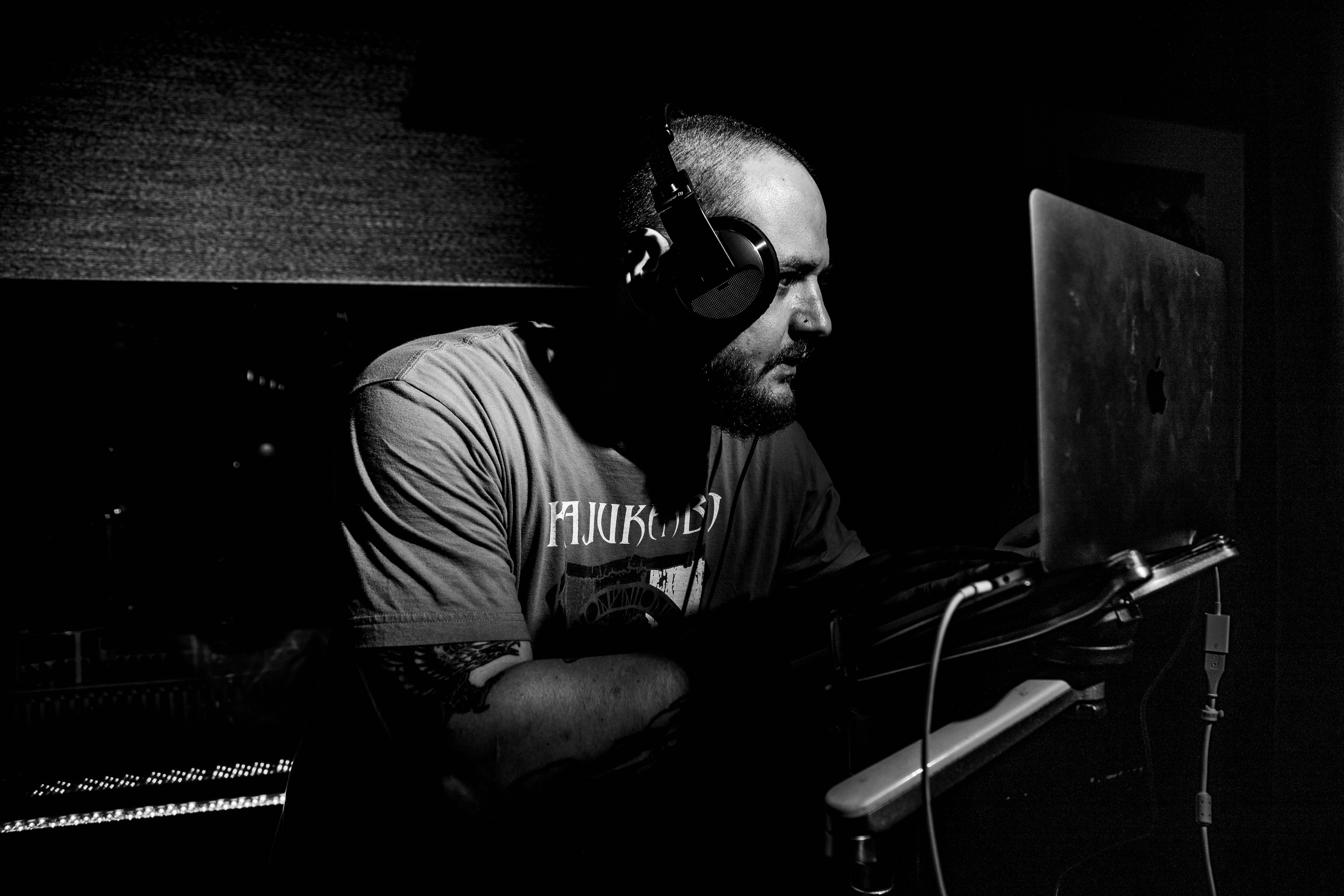 Black-and-white photograph of DJ Bear Cole working at a console with headphones